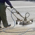 worker using equipment for water blasting on a concrete surface